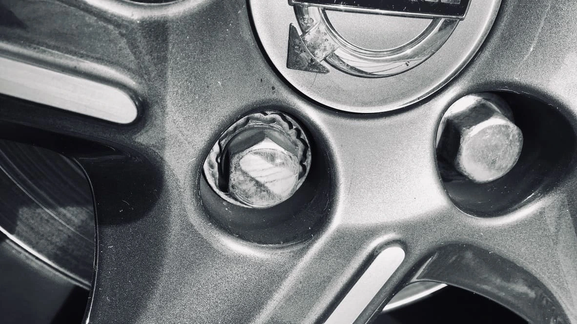 Close-up of a stripped locking wheel nut being extracted on an alloy wheel
